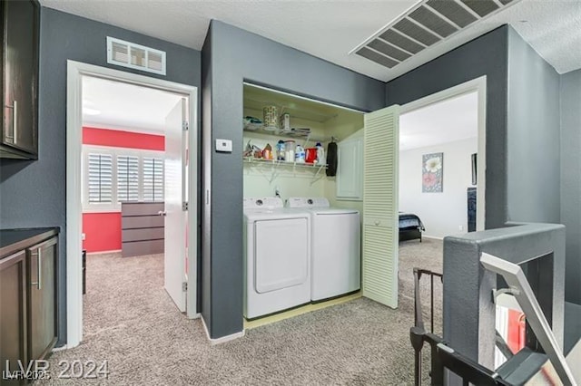 clothes washing area featuring washing machine and dryer, laundry area, visible vents, and light carpet