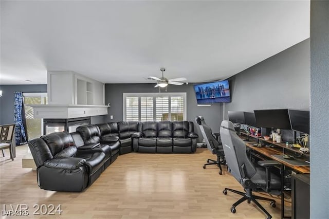 living area featuring light wood-type flooring, a wealth of natural light, ceiling fan, and a multi sided fireplace