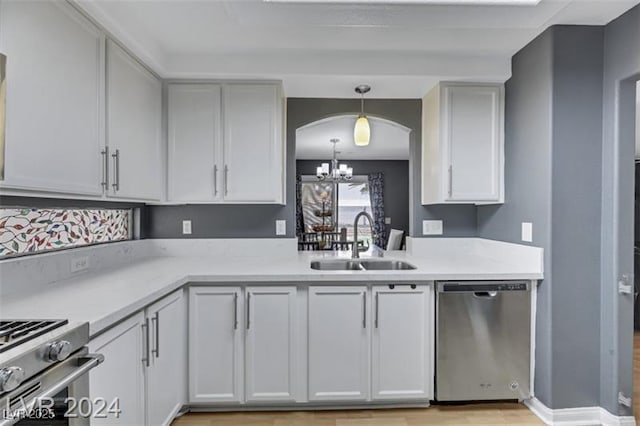 kitchen featuring arched walkways, stainless steel appliances, light countertops, an inviting chandelier, and a sink