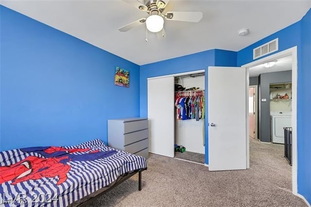 carpeted bedroom with a closet, washer / clothes dryer, visible vents, and a ceiling fan