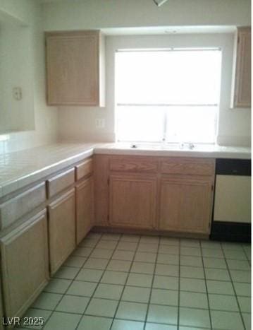 kitchen featuring light tile patterned floors, light countertops, and dishwashing machine