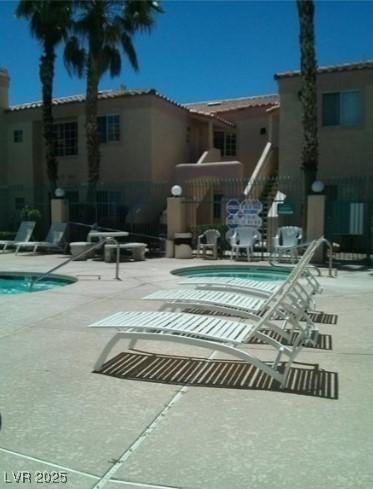 pool with a patio and a hot tub