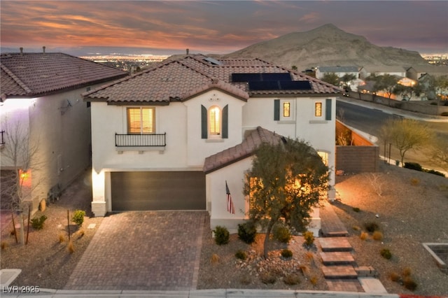 mediterranean / spanish-style home featuring a garage, solar panels, a tile roof, and stucco siding