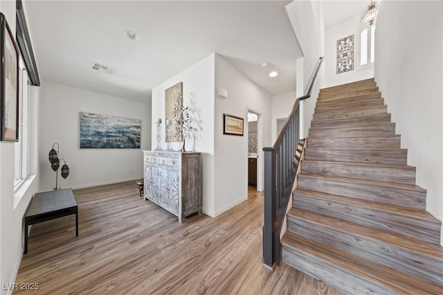 stairway featuring baseboards, wood finished floors, visible vents, and recessed lighting