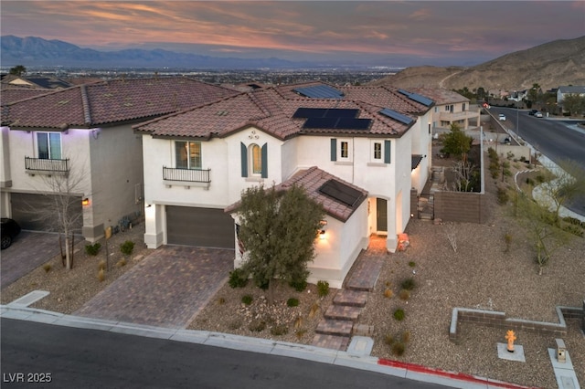 mediterranean / spanish home with a tile roof, an attached garage, decorative driveway, a mountain view, and stucco siding