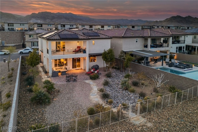 rear view of house with a patio area, solar panels, a residential view, and a balcony