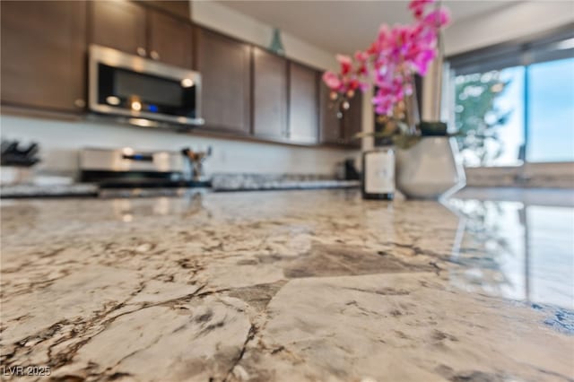 kitchen featuring stainless steel microwave, light stone counters, and stove