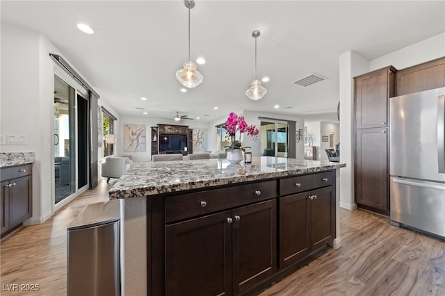 kitchen with light wood-type flooring, visible vents, open floor plan, and freestanding refrigerator