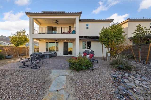 back of property with ceiling fan, a patio, a balcony, fence, and an outdoor living space