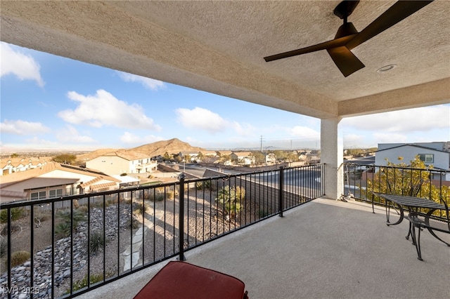 balcony with a residential view, ceiling fan, and a mountain view