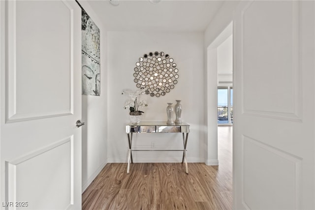 hallway featuring wood finished floors and baseboards