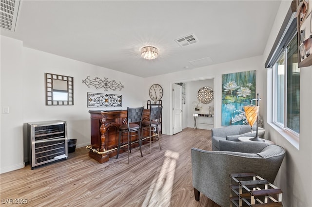 sitting room with beverage cooler, a dry bar, wood finished floors, and visible vents