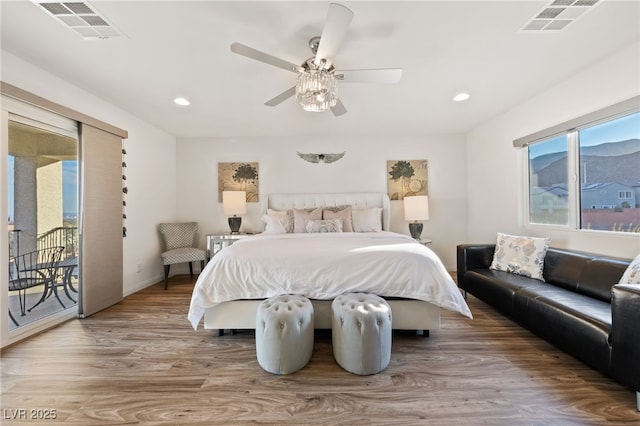 bedroom with access to outside, visible vents, ceiling fan, and wood finished floors