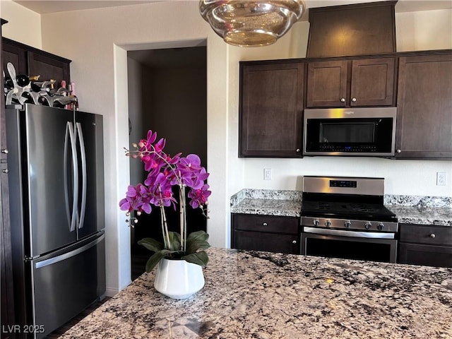 kitchen featuring stainless steel appliances, dark brown cabinets, and light stone countertops