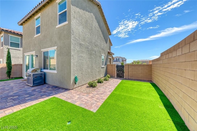 rear view of property featuring a tile roof, a fenced backyard, a patio, and stucco siding