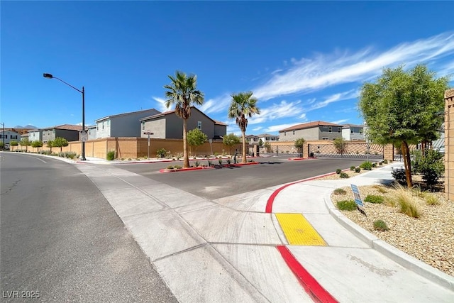 view of street featuring a residential view, curbs, sidewalks, and street lights