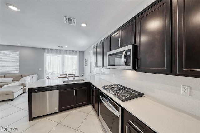 kitchen featuring visible vents, appliances with stainless steel finishes, open floor plan, a peninsula, and a sink