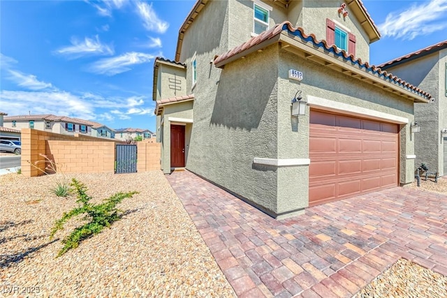 view of front of property featuring a tiled roof, an attached garage, fence, and stucco siding