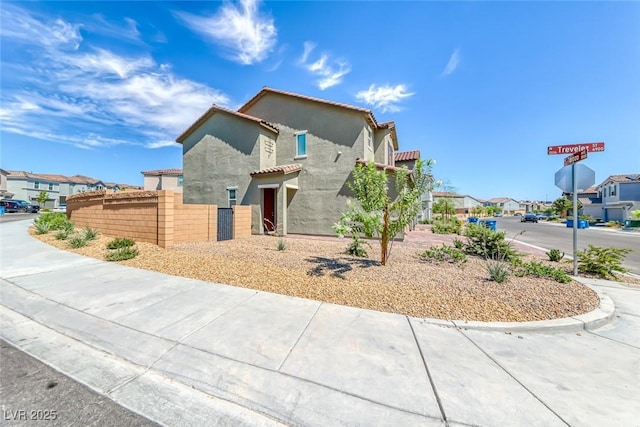 mediterranean / spanish home with a residential view, fence, a tiled roof, and stucco siding