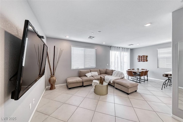 living area featuring light tile patterned floors, visible vents, baseboards, and recessed lighting