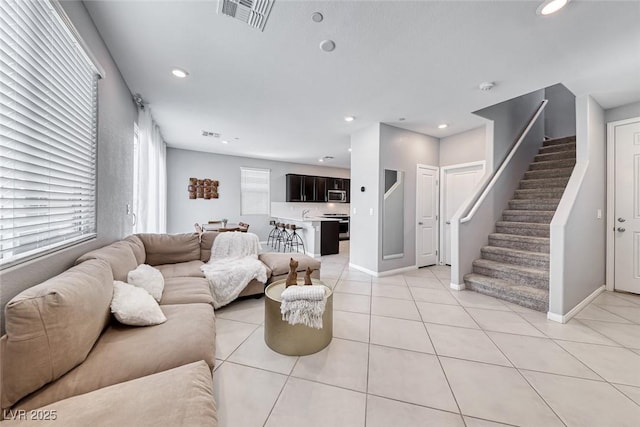 living area with light tile patterned floors, stairs, visible vents, and recessed lighting