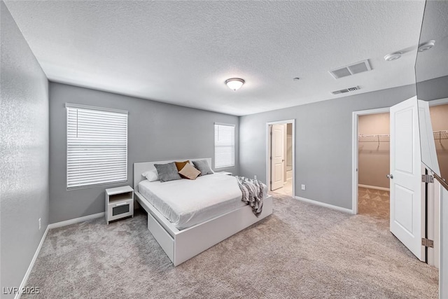 bedroom featuring carpet floors, visible vents, a spacious closet, and baseboards