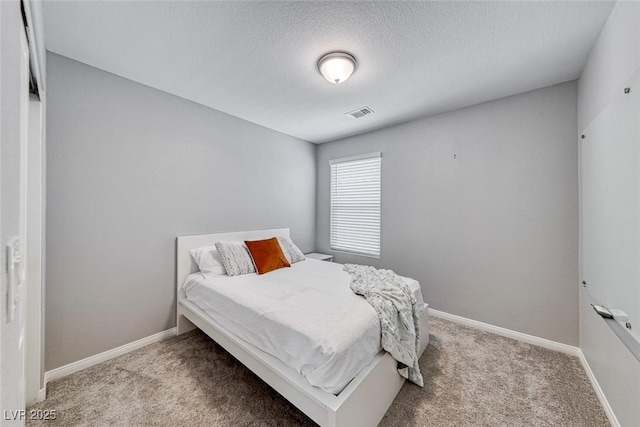 bedroom with carpet floors, visible vents, a textured ceiling, and baseboards