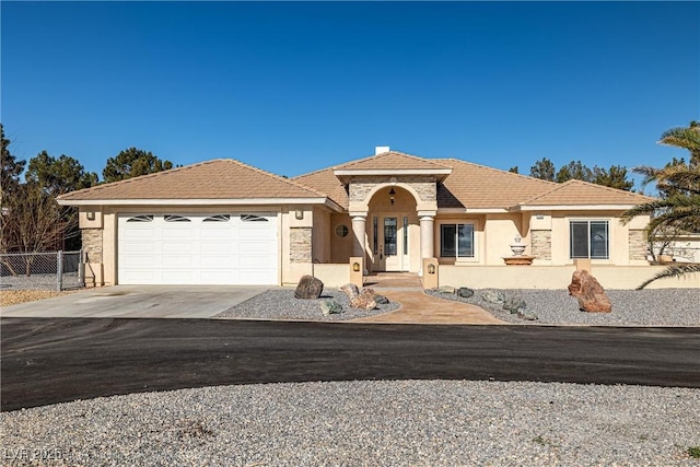 mediterranean / spanish house featuring fence, stucco siding, an attached garage, and concrete driveway