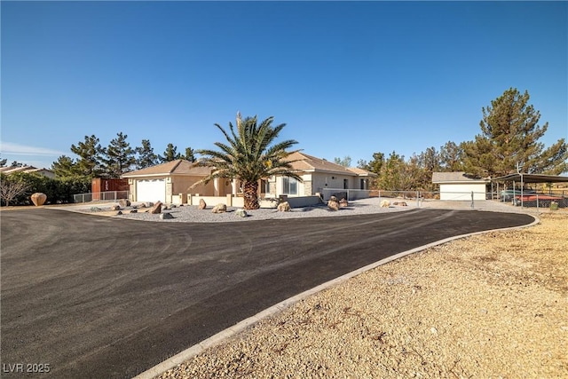 view of front facade with driveway, an attached garage, and fence