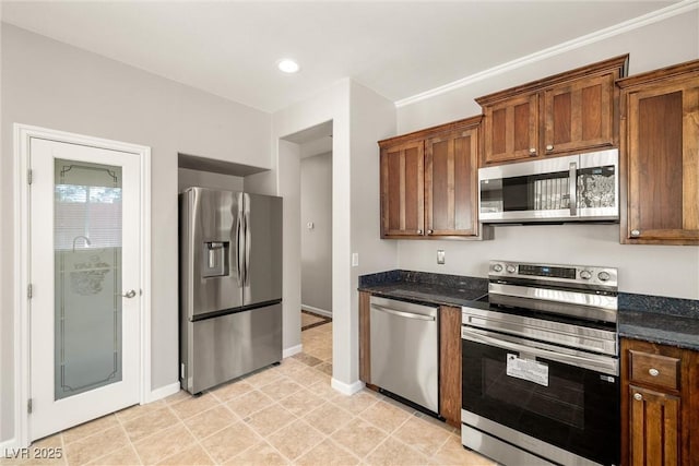 kitchen featuring baseboards, recessed lighting, appliances with stainless steel finishes, dark stone countertops, and brown cabinetry