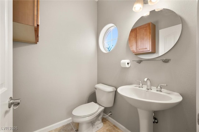 bathroom with baseboards, toilet, and tile patterned flooring