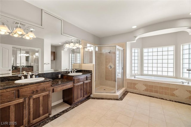 full bath featuring a bath, a shower stall, double vanity, a sink, and a notable chandelier