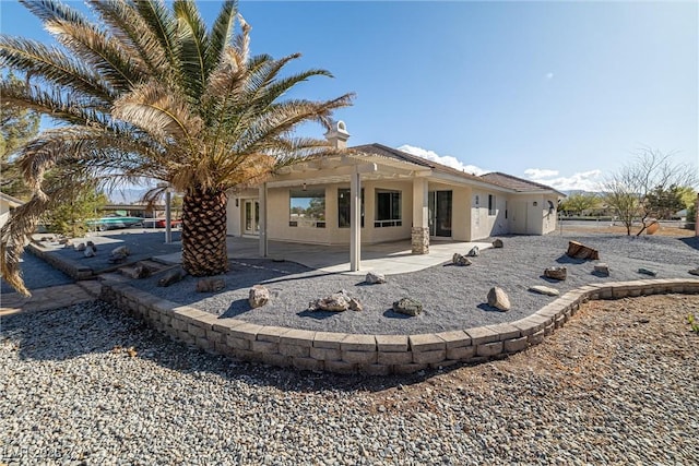 back of property with stucco siding and a patio