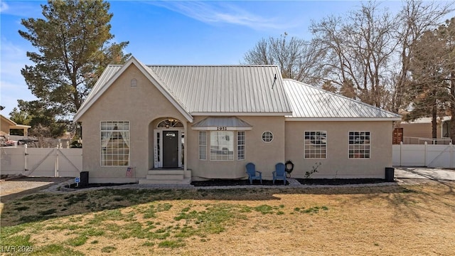 back of house with metal roof, fence, a gate, and stucco siding