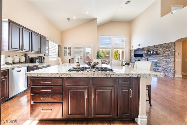 kitchen featuring stainless steel appliances, arched walkways, light wood-style flooring, and a kitchen bar