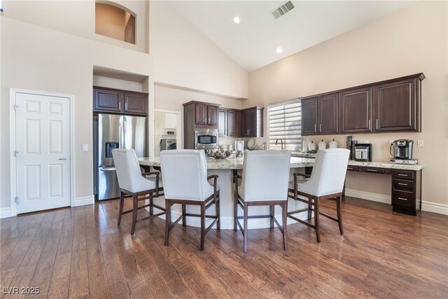 dining room with high vaulted ceiling, baseboards, visible vents, and dark wood finished floors