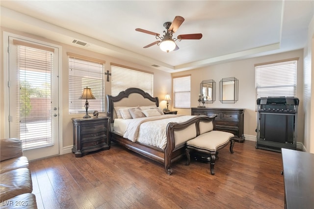 bedroom featuring dark wood-style floors, access to exterior, a raised ceiling, visible vents, and baseboards