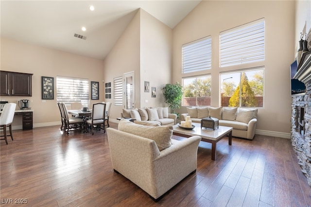 living area featuring high vaulted ceiling, plenty of natural light, visible vents, and dark wood-style flooring