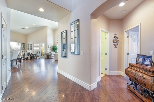 corridor featuring baseboards, arched walkways, hardwood / wood-style floors, and recessed lighting