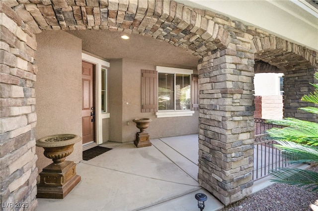 view of exterior entry featuring stone siding and stucco siding