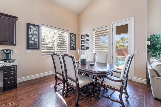 dining room with lofted ceiling, dark wood-style flooring, and baseboards