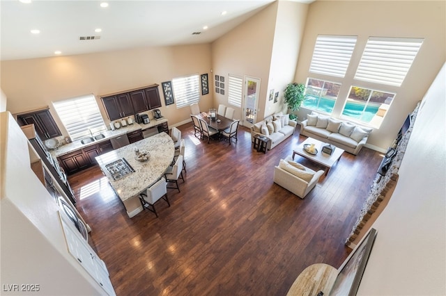 living area featuring high vaulted ceiling, recessed lighting, visible vents, baseboards, and dark wood-style floors