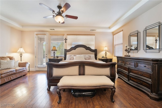 bedroom featuring access to outside, dark wood-style flooring, visible vents, and a raised ceiling