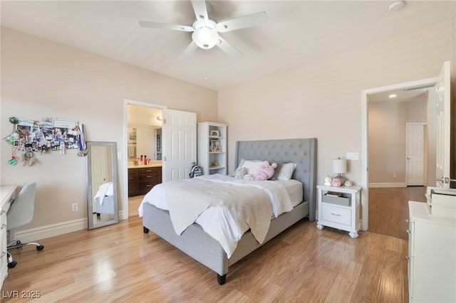 bedroom with ensuite bath, light wood-style flooring, baseboards, and ceiling fan