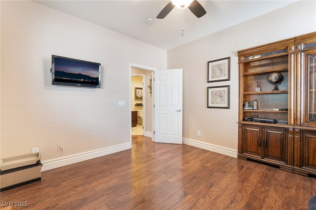 spare room with dark wood-type flooring, ceiling fan, and baseboards