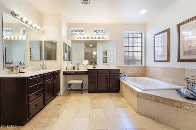 bathroom with two vanities, visible vents, a sink, and a bath