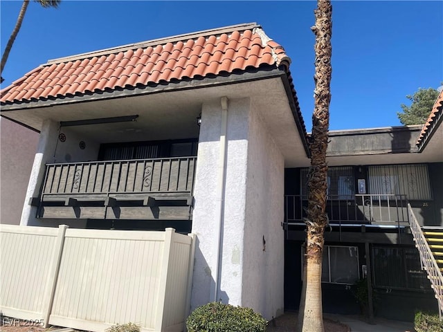 exterior space featuring a tiled roof, a balcony, and stucco siding