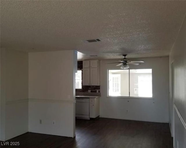 spare room with a ceiling fan, a textured ceiling, visible vents, and dark wood-type flooring