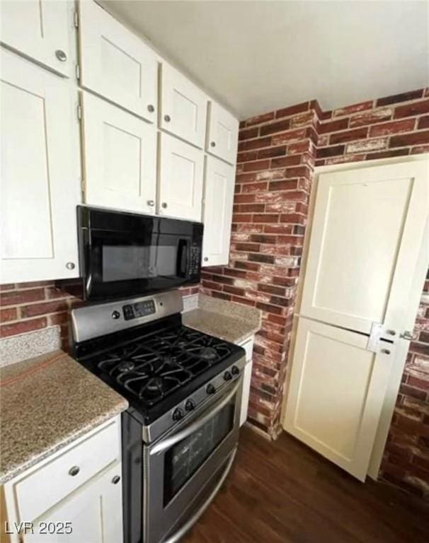 kitchen with white cabinets, light stone counters, dark wood-type flooring, black microwave, and stainless steel range with gas stovetop