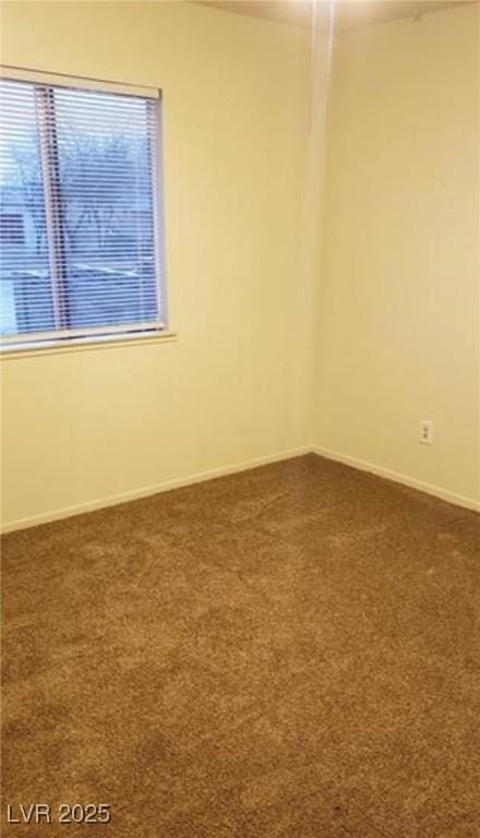 spare room with baseboards and dark colored carpet